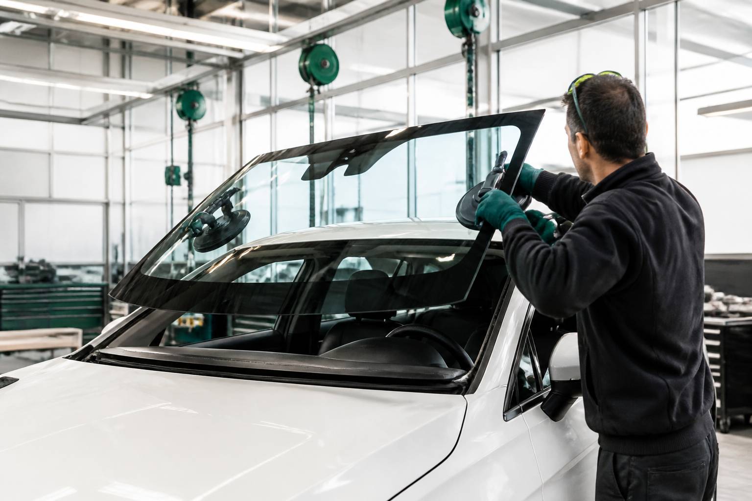 Technicien posant un pare-brise neuf avec une ventouse dans un atelier