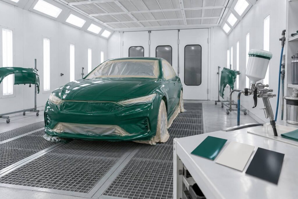 Voiture masquée dans une cabine de peinture automobile avec pistolet à peinture